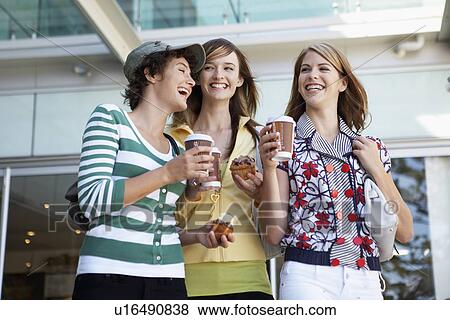Three teenage girls drinking take-out coffees and eating cakes (low angle view) View Large Photo Image Stock Photo - Three teenage girls drinking take-out coffees and eating cakes (low angle view). Fotosearch