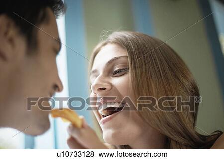 Stock Photo - Woman feeding man with cookie. Fotosearch