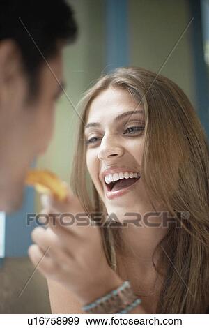 Stock Photo - Woman feeding man with cookie. Fotosearch