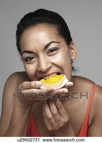 Stock Image - Young woman eating cupcake. Fotosearch