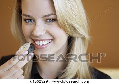 Picture - Young woman eating sushi. Fotosearch