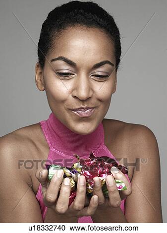Stock Image - Young woman holding candies. Fotosearch