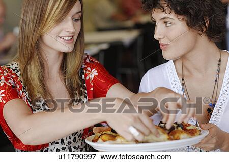 Stock Photo - Young women eating pizza. Fotosearch
