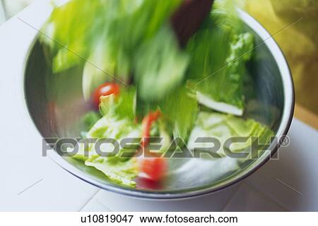 Stock Photo - Kitchen worker mixing mixed salad, Blurred Motion. Fotosearch