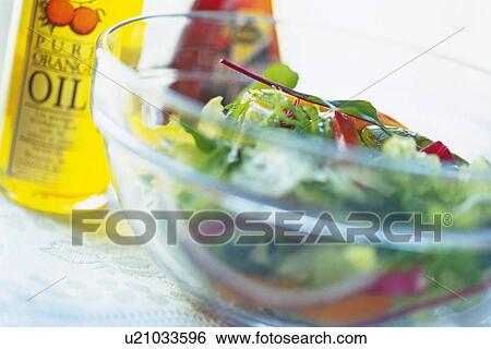 Stock Photograph - Mixed salad leaves in bowl, two bottles visible in background, Differential Focus. Fotosearch