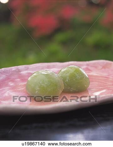 Stock Image - shi called Mizudango, Japanese sweets on plate, flower visible in background, Differential Focus. Fotosearch