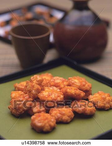 Stock Photo - Closed Up Image of a Japanese Snack, Several Fried Rice Crackers Next to Some Tea, High Angle View, Differential Focus. Fotosearch