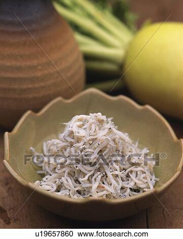 Stock Image - Closed Up Image of a Little Bowl Filled With Whitebait and a Japanese Radish in the Background, High Angle View, Differential Focus. Fotosearch