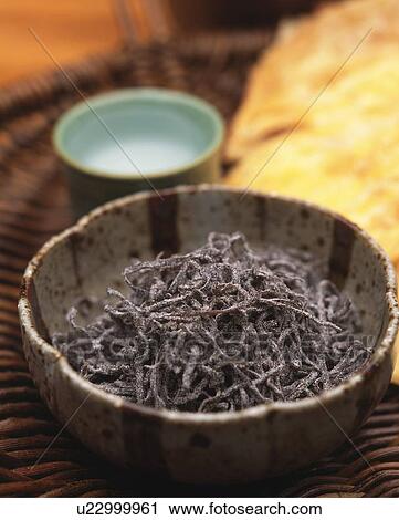Stock Image - Closed Up Image of a Little Bowl Filled With Some Seaweed Next to a Glass of Sake, High Angle View, Differential Focus. Fotosearch