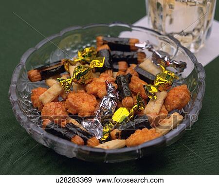 Stock Photo - Closed Up Image of a Little Glass Bowl Filled With Japanese Snacks Next to a Drink, High Angle View. Fotosearch