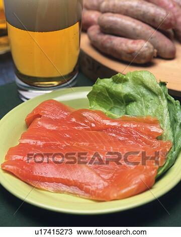 Stock Image - Closed Up Image of a Plate Full With Smoked Salmon, Sausages and a Glass of Beer, High Angle View. Fotosearch