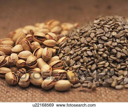 Stock Photo - Closed Up Image of Several Pistachios and Some Sunflower Seeds on a Beige-colored Surface. Fotosearch