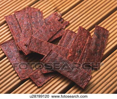 Stock Image - Closed Up Image of Several Slices of Beef Jerky on a Wooden Surface, High Angle View. Fotosearch