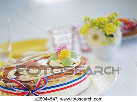 Stock Photo - Cheese cake with whipped cream and vase of flowers on table. Fotosearch