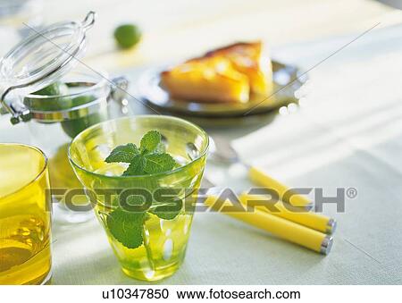 Stock Image - Herb in a glass and slices of orange tart on plate. Fotosearch