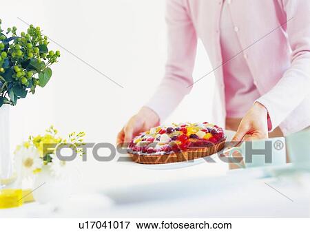 Stock Photo - Woman holding a plate with fruit tart. Fotosearch