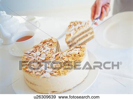 Stock Photo - Woman serving cake strewed with almond slices . Fotosearch