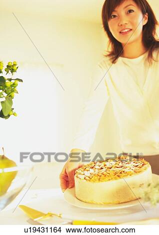 Picture - Young woman holding plate with cake. Fotosearch