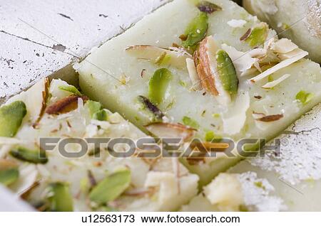 Stock Image - Close-up of Burfi garnished with Almond and Pistachio. Fotosearch