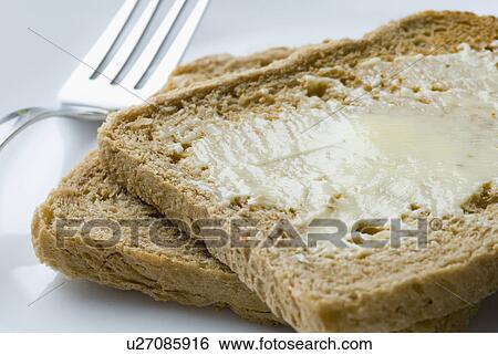 Stock Photograph - Close-up of butter on brown bread with a fork. Fotosearch