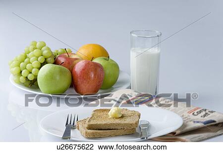 Stock Image - Close-up of fruits and brown bread with butter in a plate. Fotosearch