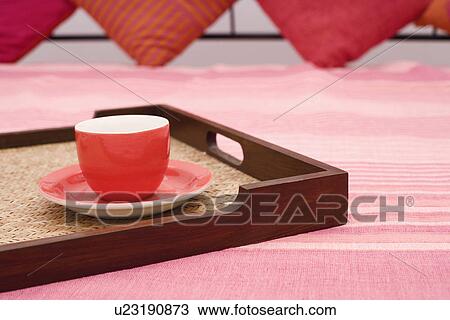 Stock Image - Tea cup in a tray on the bed. Fotosearch