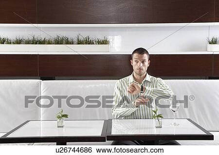 Stock Photograph - Businessman checking time in restaurant. Fotosearch