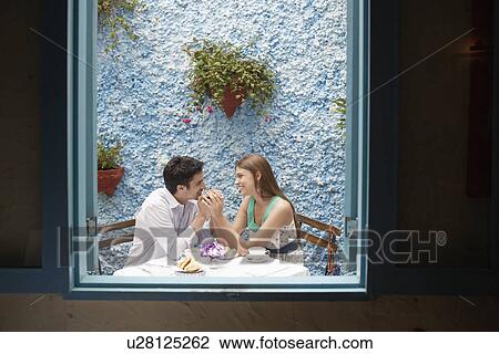 Stock Image - Couple holding hands in restaurant. Fotosearch