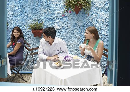 Stock Image - Couple talking to woman in restaurant. Fotosearch
