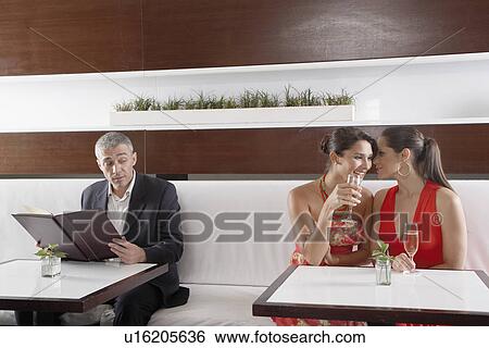 Man listening to two women whispering in restaurant View Large Photo Image Stock Photograph - Man listening to two women whispering in restaurant. Fotosearch