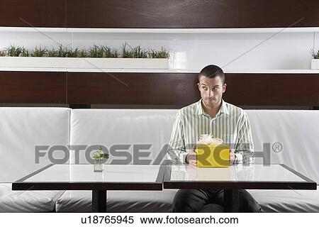 Stock Photography - Man with present waiting in restaurant. Fotosearch