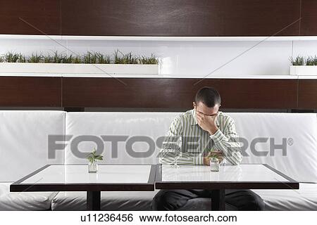 Stock Photograph - Stressed businessman leaning on hand in restaurant. Fotosearch
