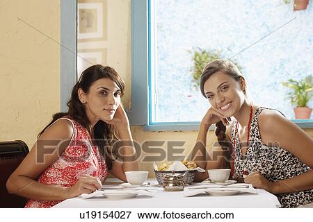 Stock Photo - Two women at dining table in restaurant (portrait). Fotosearch