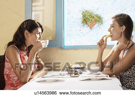 Two women eating and drinking in restaurant View Large Photo Image Stock Photograph - Two women eating and drinking in restaurant. Fotosearch