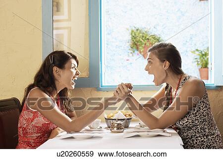 Two women laughing and screaming at table View Large Photo Image Stock Photo - Two women laughing and screaming at table. Fotosearch