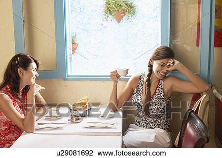 Stock Image - Two women talking at dining table in restaurant. Fotosearch