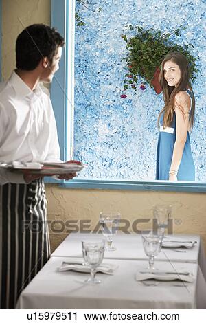 Stock Image - Waiter flirting with woman at window. Fotosearch