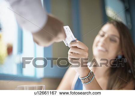 Stock Photo - Woman giving credit card to man (close-up). Fotosearch