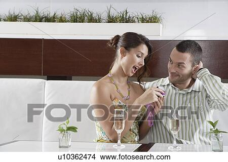 Woman opening gift next to boyfriend View Large Photo Image Picture - Woman opening gift next to boyfriend. Fotosearch