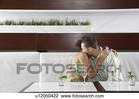 Stock Image - Woman with gift hugging man. Fotosearch