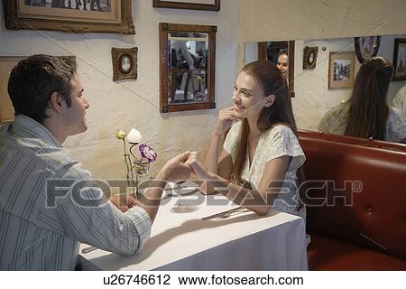 Young couple holding hands in restaurant View Large Photo Image Stock Image - Young couple holding hands in restaurant. Fotosearch