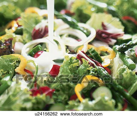 Stock Image - Salad with dressing being poured on it. Fotosearch