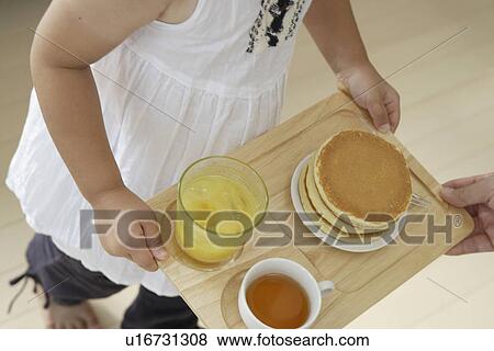 Stock Photo - A girl carrying a tray with some pancakes. Fotosearch