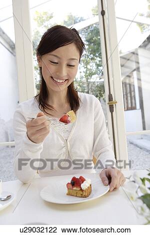 Stock Image - A young woman eating pastry with a fork. Fotosearch