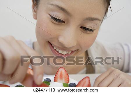 Stock Image - Close-up of a young woman garnishing a pastry. Fotosearch