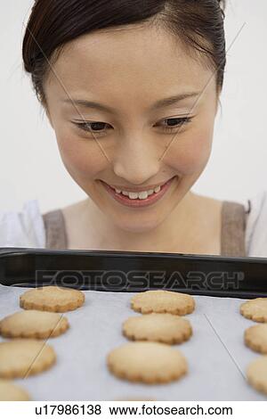 Close-up of a young woman looking at a biscuit tray View Large Photo Image Stock Photo - Close-up of a young woman looking at a biscuit tray. Fotosearch