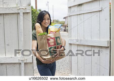 Portrait of a woman holding groceries with paper bag View Large Photo Image Stock Image - Portrait of a woman holding groceries with paper bag. Fotosearch