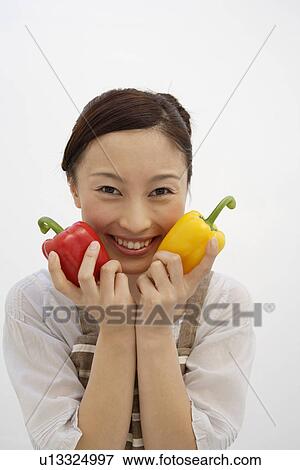 Portrait of a young woman holding bell peppers View Large Photo Image Stock Photo - Portrait of a young woman holding bell peppers. Fotosearch