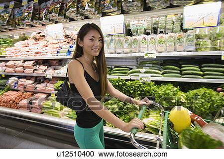 Stock Image - Portrait of a young woman shopping in supermarket. Fotosearch