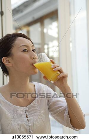 Stock Image - View of a young woman drinking juice. Fotosearch